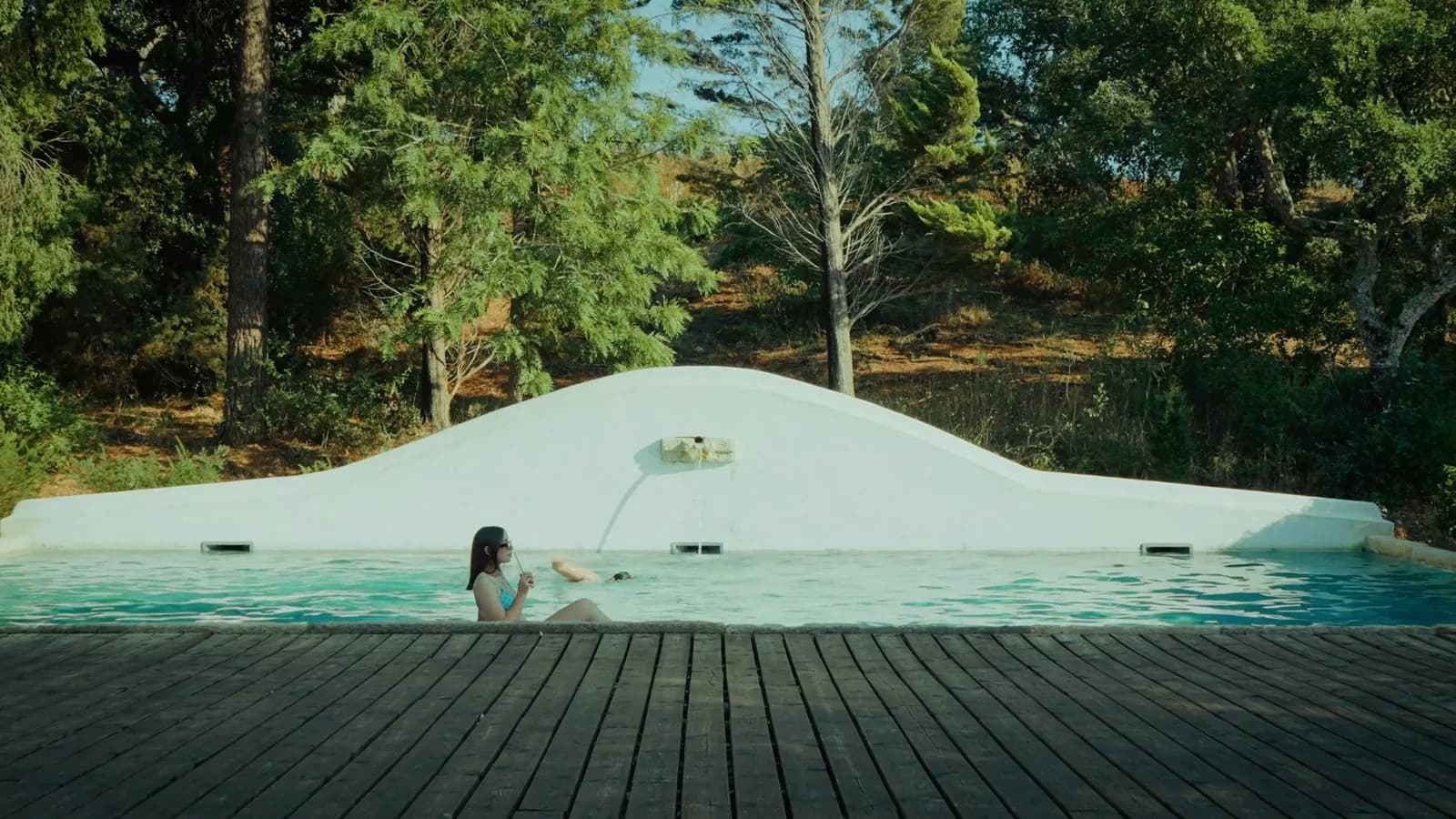 Uma hóspede na piscina do Hotel Casa Palmela, rodeada de árvores