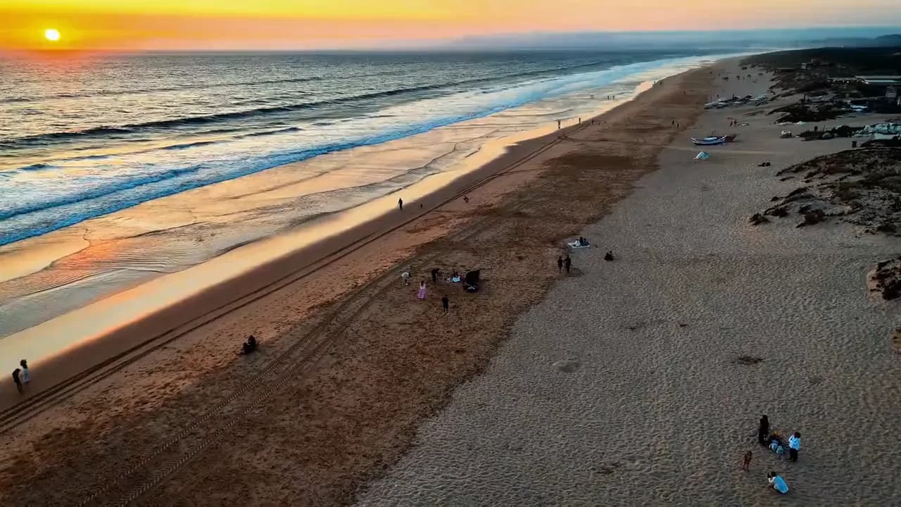 A praia ao pôr do sol vista do ar, no filme do casamento de Carina e Victor