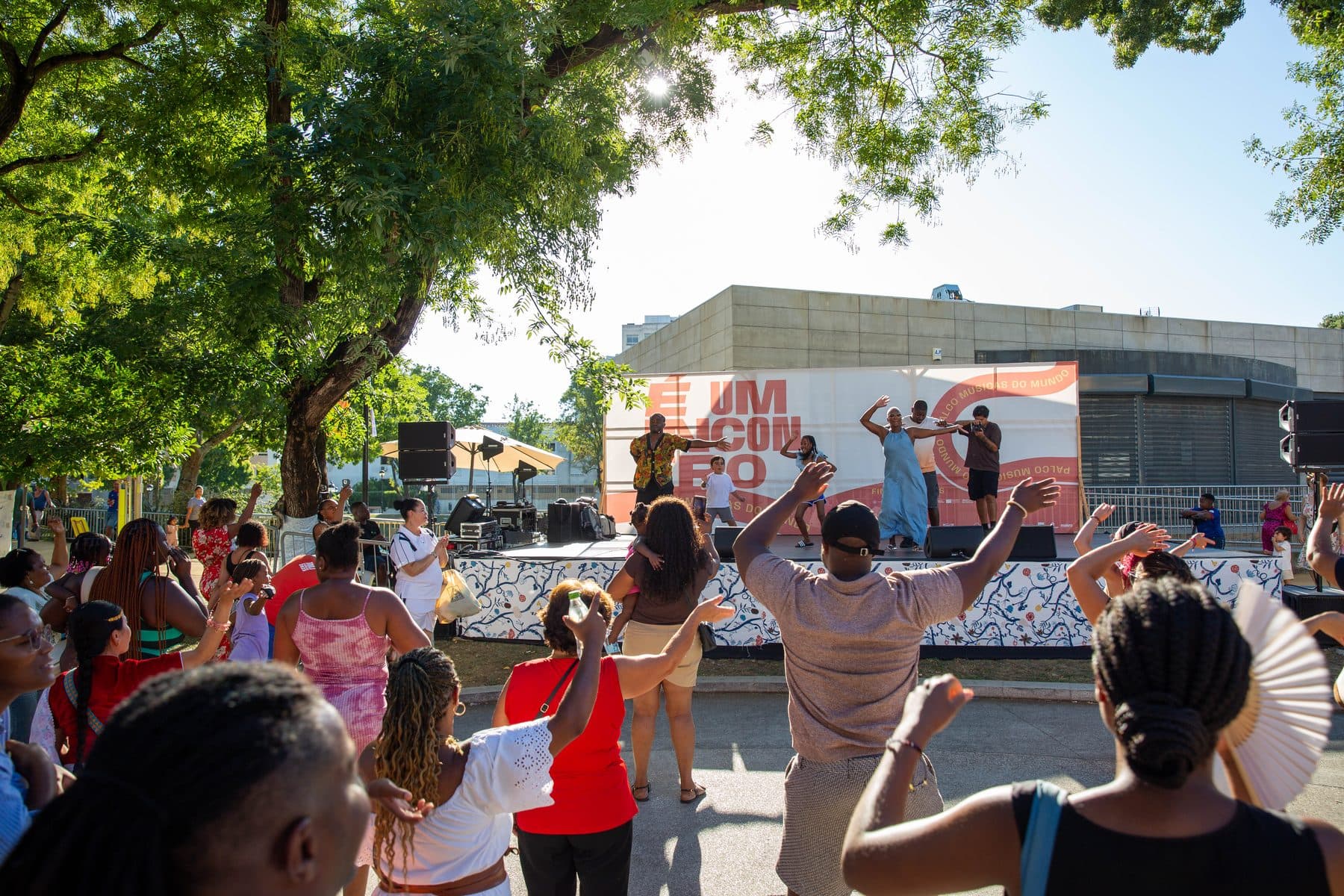 Público a dançar de braços no ar em frente ao palco, a acompanhar quem dança lá em cima