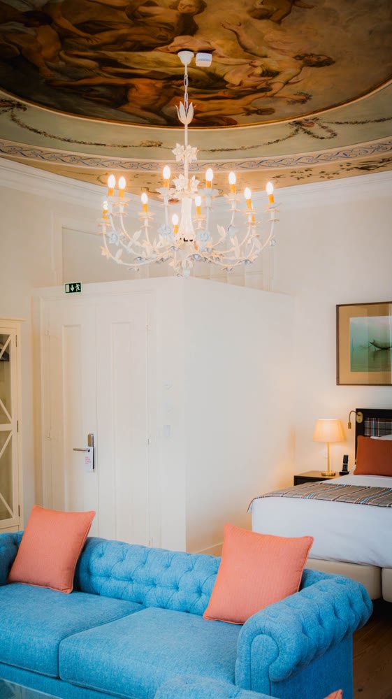 Room with a painted ceiling, a chandelier and a blue sofa at Once Upon Lisboa