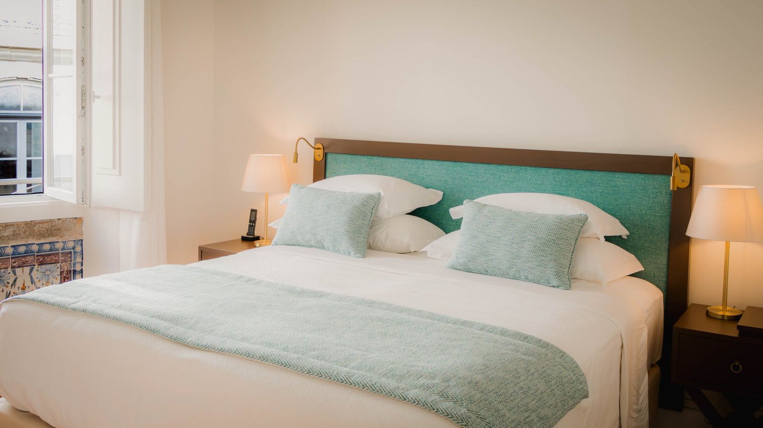 Bed with a pale green headboard and bedside lamps at Once Upon Lisboa