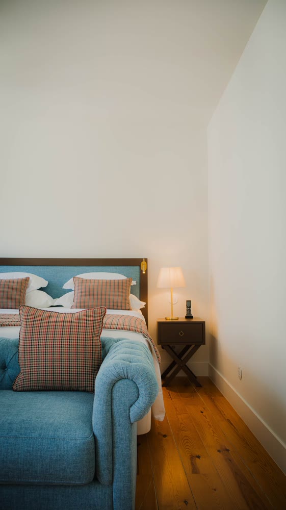 Corner of a room with a blue sofa and the bed behind
